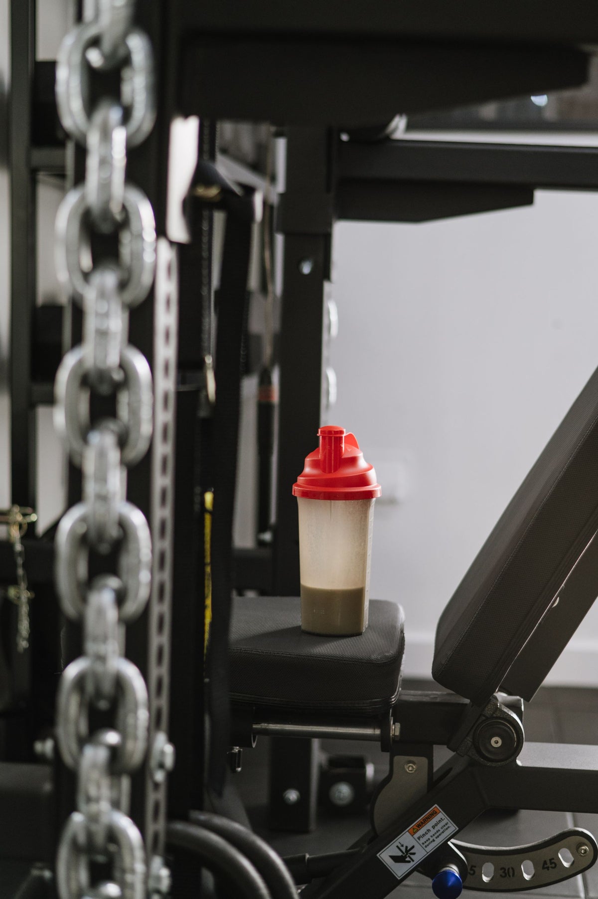 Protein shaker bottle standing on gym equipment