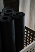 Black non-slip exercise mats rolled and stacked
