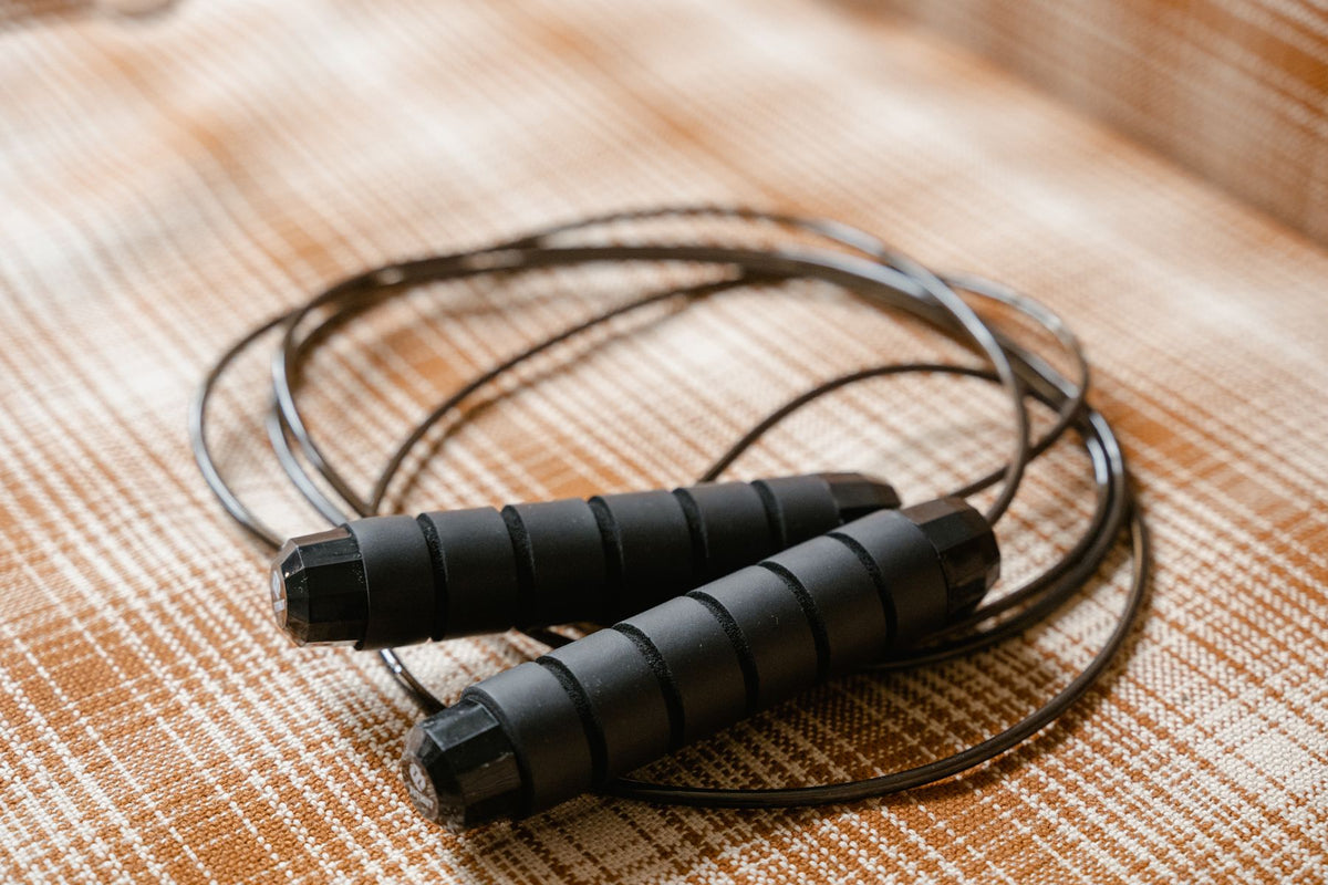 Black speed jump rope coiled on a mat